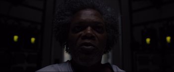 Movie still from “Glass” (2019), directed by M. Night Shyamalan – A person's face in the dark; Close Up shot, Low angle