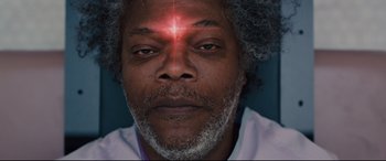 Movie still from “Glass” (2019), directed by M. Night Shyamalan – A person wearing a white shirt with a light shining on his forehead; Extreme Close Up shot, Overhead angle