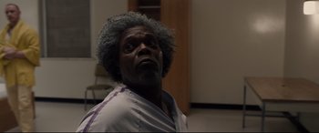 Movie still from “Glass” (2019), directed by M. Night Shyamalan – An older man with grey hair looking at the camera; Close Up shot, Low angle