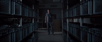 Movie still from “Glass” (2019), directed by M. Night Shyamalan – A man standing in a room full of boxes; Wide shot, Low angle