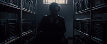 Movie still from “Glass” (2019), directed by M. Night Shyamalan – A man sitting in a chair in a dark room; Medium shot, Low angle