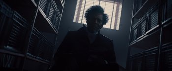 Movie still from “Glass” (2019), directed by M. Night Shyamalan – A man in a black suit standing next to a window; Close Up shot, Low angle