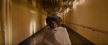 Movie still from “Glass” (2019), directed by M. Night Shyamalan – A person wrapped in a blanket in a hallway; Wide shot, High angle