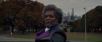Movie still from “Glass” (2019), directed by M. Night Shyamalan – An older black man wearing a suit and purple tie; Close Up shot, Low angle