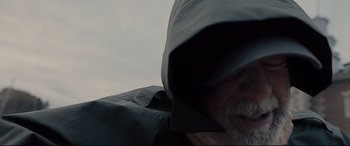Movie still from “Glass” (2019), directed by M. Night Shyamalan – A man wearing a hooded jacket and a gray hat; Close Up shot, Low angle