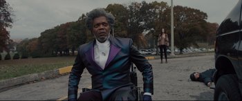 Movie still from “Glass” (2019), directed by M. Night Shyamalan – A man in a purple suit sitting on a motorcycle; Medium shot, Low angle