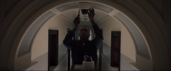 Movie still from “Glass” (2019), directed by M. Night Shyamalan – A man is holding a light in a room; Medium shot, Low angle