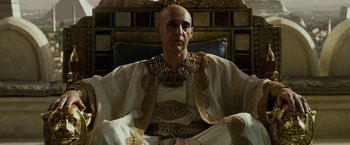 Movie still from “Exodus: Gods and Kings” (2014), directed by Ridley Scott – A bald man wearing a white robe and gold jewelry; Medium shot, Low angle