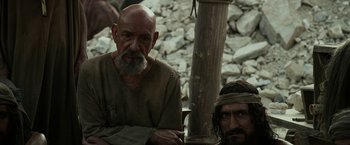 Movie still from “Exodus: Gods and Kings” (2014), directed by Ridley Scott – Two men sitting next to each other on a rock pile; Medium shot, Over the shoulder angle