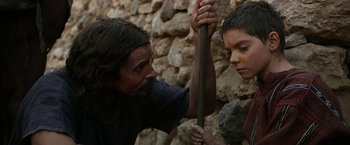 Movie still from “Exodus: Gods and Kings” (2014), directed by Ridley Scott – A man and a young boy holding onto a stick; Medium shot, Over the shoulder angle