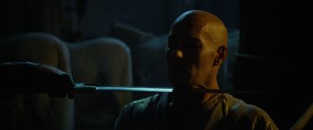 Movie still from “Exodus: Gods and Kings” (2014), directed by Ridley Scott – A bald man holding a sword in a dark room; Close Up shot, Low angle