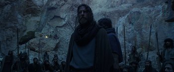 Movie still from “Exodus: Gods and Kings” (2014), directed by Ridley Scott – A man with long hair and a beard standing in front of a rock wall; Medium shot, Low angle