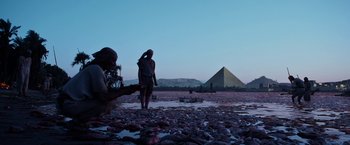 Movie still from “Exodus: Gods and Kings” (2014), directed by Ridley Scott – Two people standing on a beach near a pyramid; Extreme Wide shot, Low angle