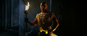 Movie still from “Exodus: Gods and Kings” (2014), directed by Ridley Scott – A man holding a torch in a dark room; Medium shot, Low angle