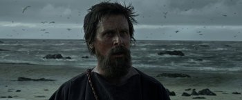 Movie still from “Exodus: Gods and Kings” (2014), directed by Ridley Scott – A man with long hair and a beard standing in front of a body of water; Close Up shot, Low angle