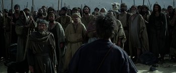 Movie still from “Exodus: Gods and Kings” (2014), directed by Ridley Scott – A group of men in robes and headgear are gathered together; Wide shot, Over the shoulder angle