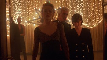 Movie still from “Eyes Wide Shut” (1999), directed by Stanley Kubrick – A woman in a black dress standing next to a man in a suit; Medium shot, Low angle