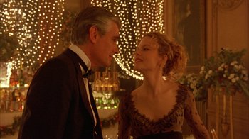 Movie still from “Eyes Wide Shut” (1999), directed by Stanley Kubrick – A man and a woman standing next to each other in front of lights; Medium shot, Over the shoulder angle