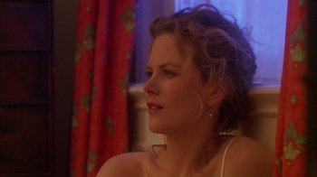 Movie still from “Eyes Wide Shut” (1999), directed by Stanley Kubrick – A beautiful woman sitting in front of a red curtain; Close Up shot, Over the shoulder angle
