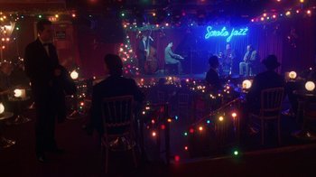 Movie still from “Eyes Wide Shut” (1999), directed by Stanley Kubrick – People are sitting in a room decorated with lights; Extreme Wide shot, High angle