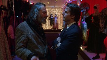 Movie still from “Eyes Wide Shut” (1999), directed by Stanley Kubrick – Two men in suits talking to each other in a room; Close Up shot, Over the shoulder angle