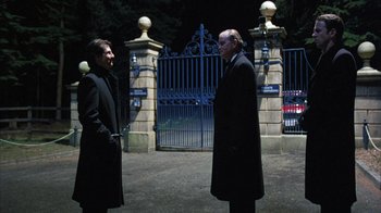 Movie still from “Eyes Wide Shut” (1999), directed by Stanley Kubrick – Two men standing next to each other in front of a gate; Wide shot, Over the shoulder angle