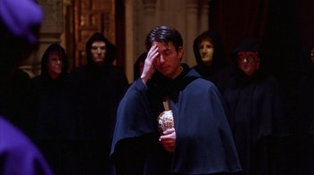 Movie still from “Eyes Wide Shut” (1999), directed by Stanley Kubrick – A man in a hooded cloak holding a can of beer; Medium shot, Over the shoulder angle