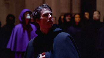 Movie still from “Eyes Wide Shut” (1999), directed by Stanley Kubrick – A man wearing a black robe and a black cape; Medium shot, Over the shoulder angle