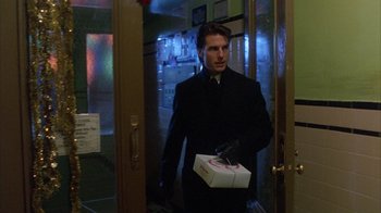 Movie still from “Eyes Wide Shut” (1999), directed by Stanley Kubrick – A man in a black jacket holding a box; Medium shot, Low angle