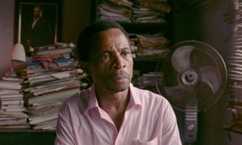 A man sitting in front of a fan in a room