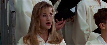 Movie still from “Face/Off” (1997), directed by John Woo – A woman with long blonde hair is holding a book in her hand; Close Up shot, Over the shoulder angle