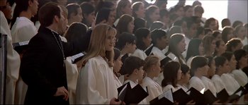 Movie still from “Face/Off” (1997), directed by John Woo – A group of young people in choir robes holding books; Medium shot, High angle