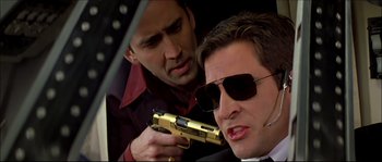 Movie still from “Face/Off” (1997), directed by John Woo – A man holding a gun next to another man in a car; Close Up shot, Low angle