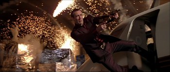Movie still from “Face/Off” (1997), directed by John Woo – A man in a suit and tie holding a gun; Medium shot, Low angle