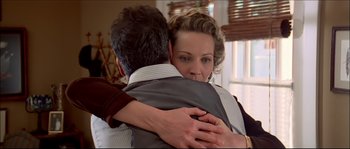 Movie still from “Face/Off” (1997), directed by John Woo – A woman is hugging a man in a suit; Close Up shot, Low angle