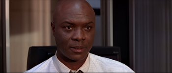 Movie still from “Face/Off” (1997), directed by John Woo – A man with a bald head is sitting in a chair; Close Up shot, Low angle