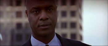 Movie still from “Face/Off” (1997), directed by John Woo – A person wearing a suit and tie; Close Up shot, Low angle