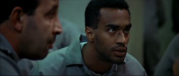 Movie still from “Face/Off” (1997), directed by John Woo – A man in a gray shirt is looking into the distance; Close Up shot, Over the shoulder angle