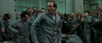 Movie still from “Face/Off” (1997), directed by John Woo – A group of men in grey suits are standing in a room; Medium shot, Low angle