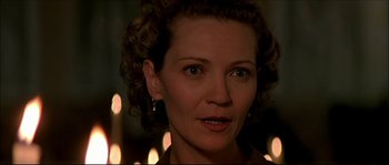 Movie still from “Face/Off” (1997), directed by John Woo – A person wearing earrings with candles in the background; Close Up shot, Over the shoulder angle