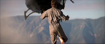 Movie still from “Face/Off” (1997), directed by John Woo – A man jumping in the air with his feet in the air; Wide shot, Low angle