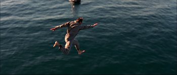 Movie still from “Face/Off” (1997), directed by John Woo – A man jumping in the air over a body of water; Wide shot, Overhead angle