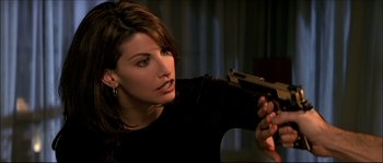 Movie still from “Face/Off” (1997), directed by John Woo – A beautiful woman holding a gun in a room; Close Up shot, Over the shoulder angle