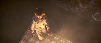 Movie still from “Face/Off” (1997), directed by John Woo – A person standing on top of a metal structure at night; Wide shot, Overhead angle