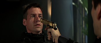 Movie still from “Face/Off” (1997), directed by John Woo – A man holding a gun up to his face; Close Up shot, Over the shoulder angle