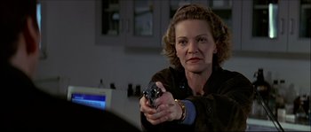 Movie still from “Face/Off” (1997), directed by John Woo – A woman is holding a gun in her hand; Close Up shot, Over the shoulder angle