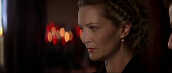 Movie still from “Face/Off” (1997), directed by John Woo – A person wearing a black shirt with lights in the background; Close Up shot, Over the shoulder angle