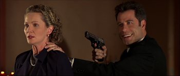 Movie still from “Face/Off” (1997), directed by John Woo – A man holding a gun in front of a woman; Close Up shot, Over the shoulder angle
