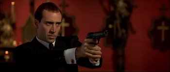 Movie still from “Face/Off” (1997), directed by John Woo – A man in a suit and tie holding a gun in his hand; Close Up shot, Low angle