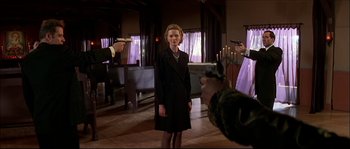 Movie still from “Face/Off” (1997), directed by John Woo – A woman standing in a room with a gun in her hand; Medium shot, Over the shoulder angle